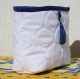 Pochette en coton blanc et liseret bleu avec fermeture éclair ornée d'un pompon et d'un bouton bleu 