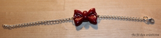 Bracelet en métal argenté avec son noeud rouge pailleté en fimo 